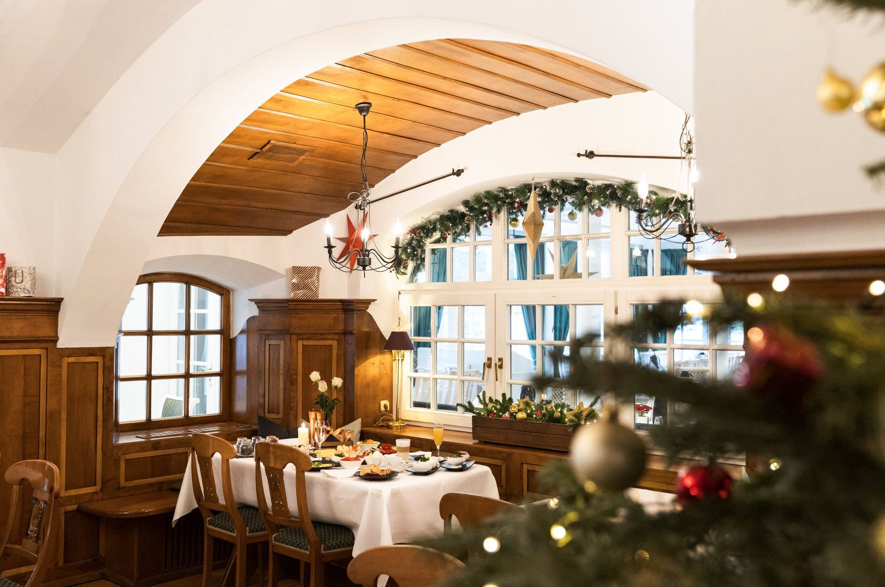 Adventlich geschmücktes Restaurant mit Christbaum und gedeckten Tischen