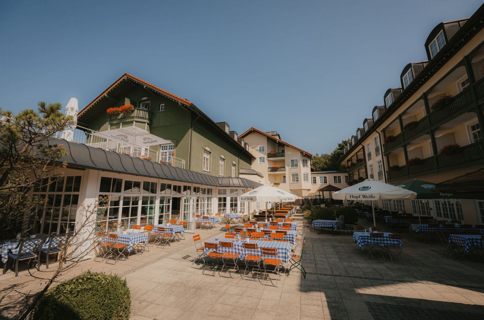 Biergarten mit Bänken und Schirmen vor dem Hotel