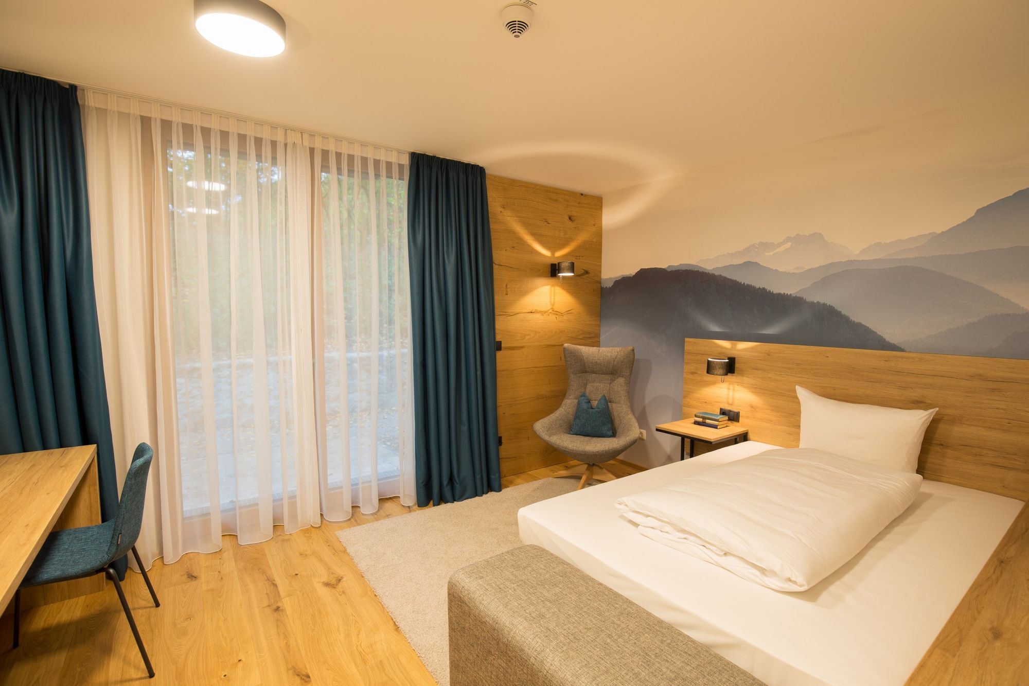 Comfort Apartment in the Leo Apartments Miesbach with wooden floor, wooden furniture and a mountain motif on the wall