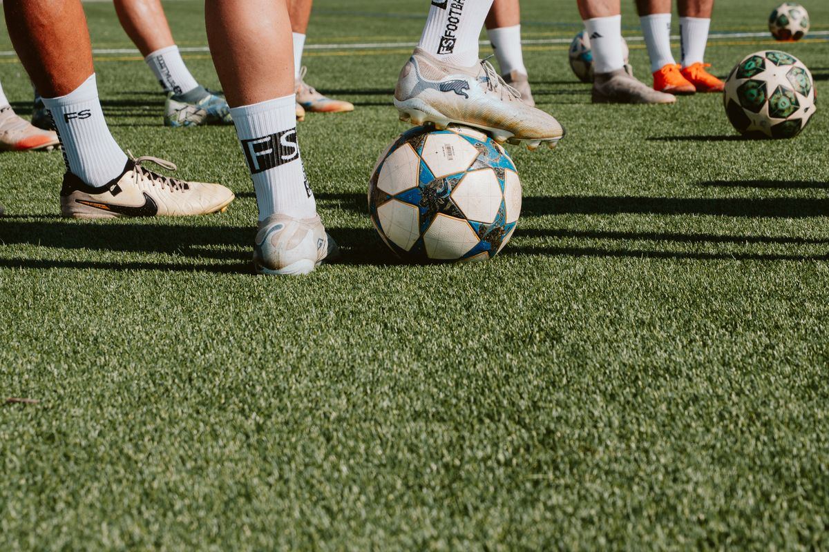 Football boots and balls in a row on the grass
