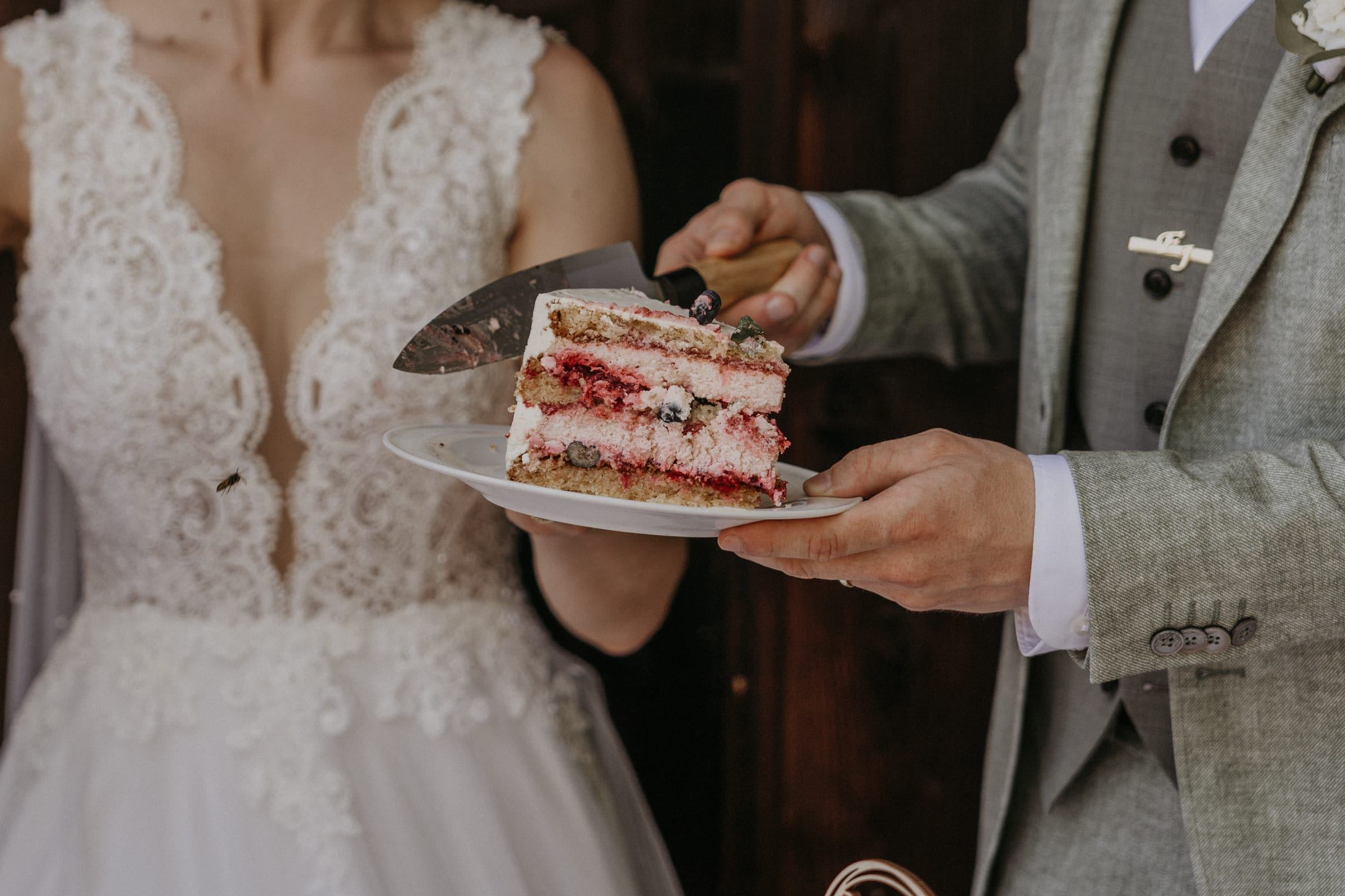 Das Brautpaar serviert ein Stück Hochzeitstorte