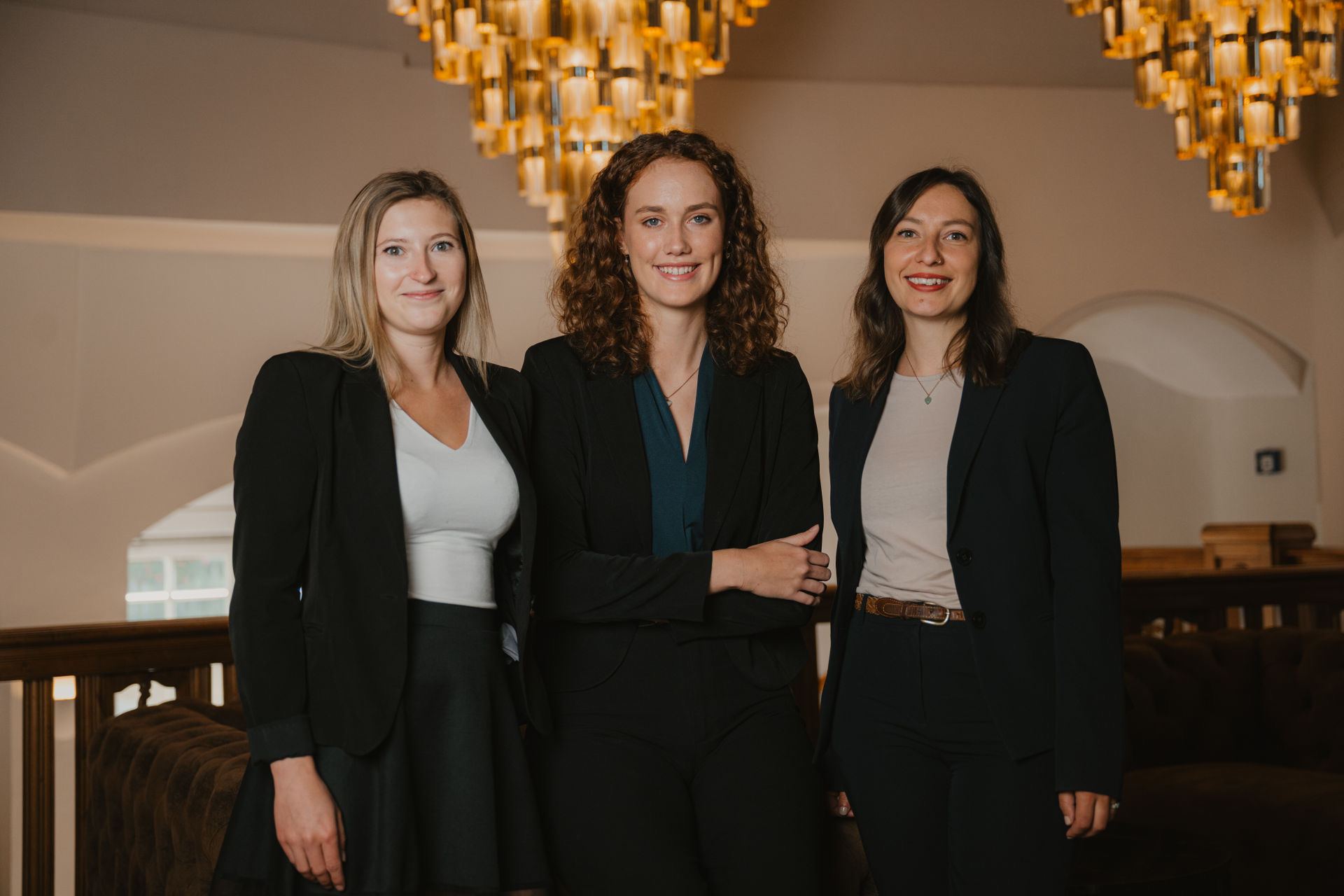 Three colleagues from the Bayerischer Hof team beneath the chandeliers in the lobby