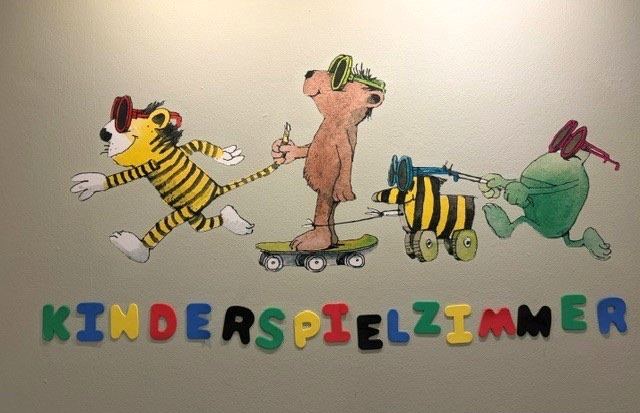 Bemalte Wand im Kinderspielzimmer des Bayerischen Hofs: Tiger, Bär und Tigerente über dem bunten Schriftzug „Kinderspielzimmer“