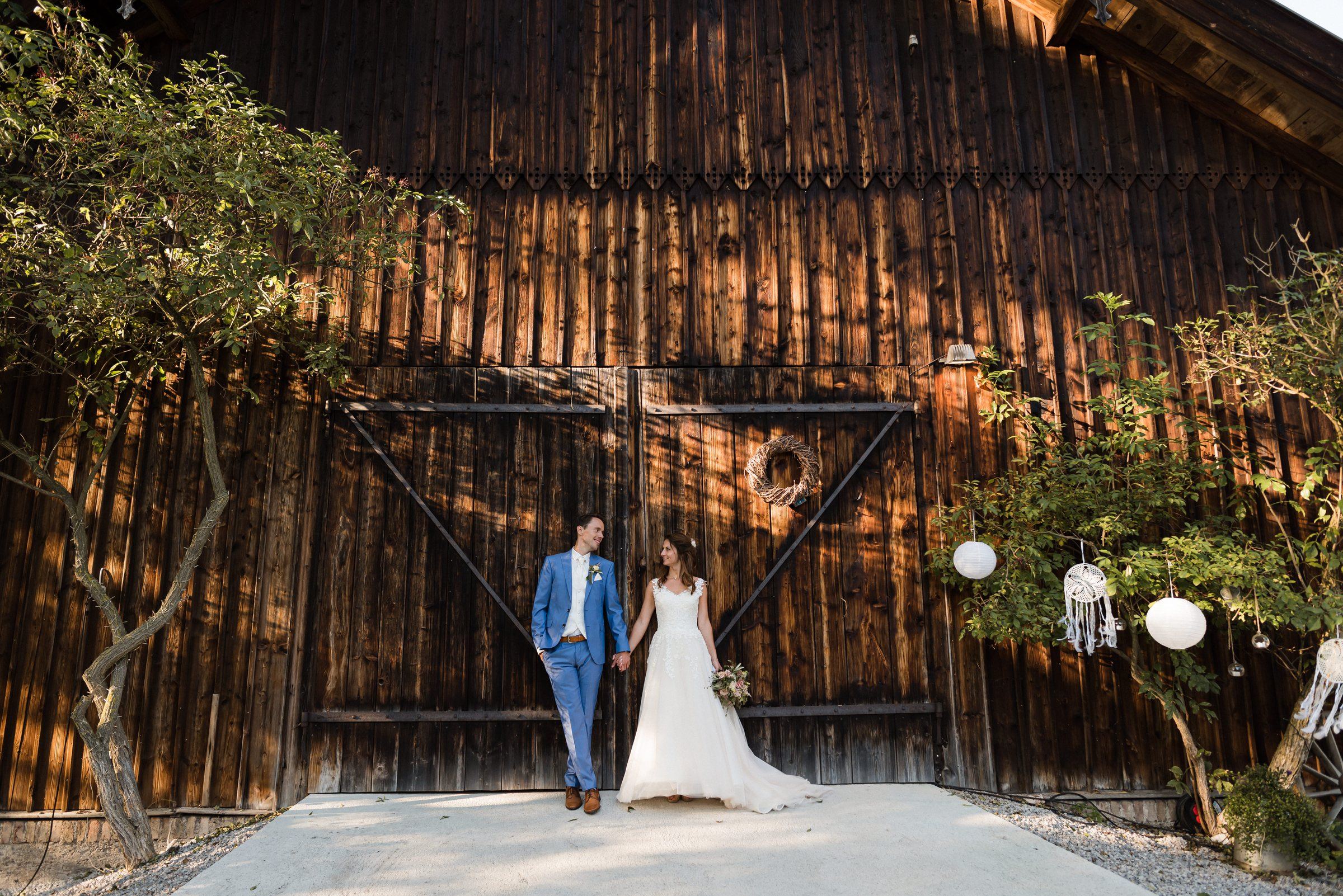 Das Brautpaar vor dem großen Holztor der EVENTSCHEUNE