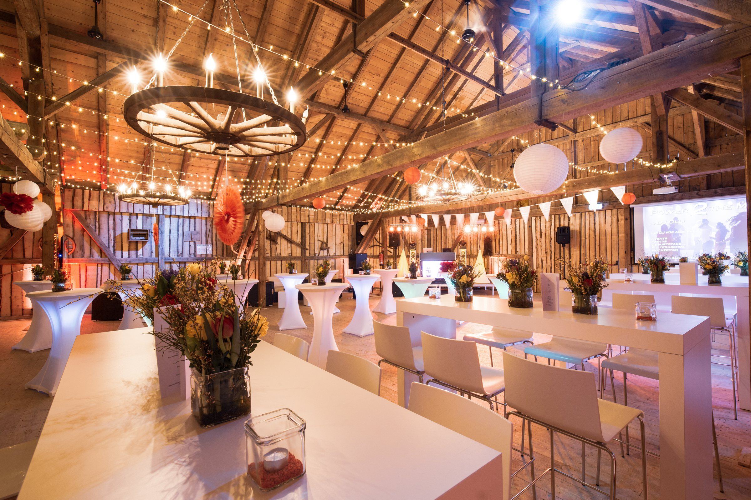 Lange Hochtische mit Barhockern und Blumen in der EVENTSCHEUNE