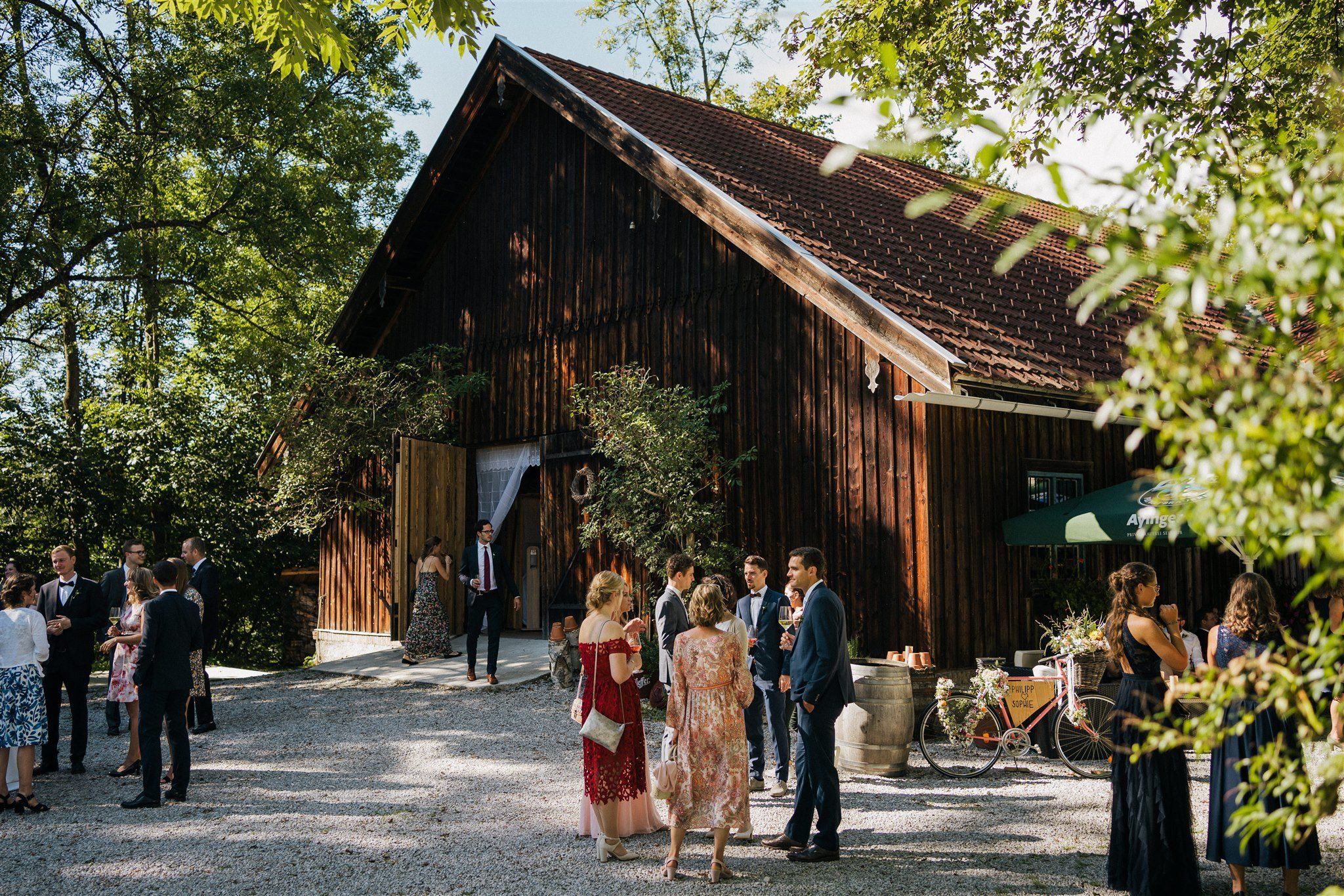 Hochzeitsgäste im Hof vor der Scheune in der Sonne