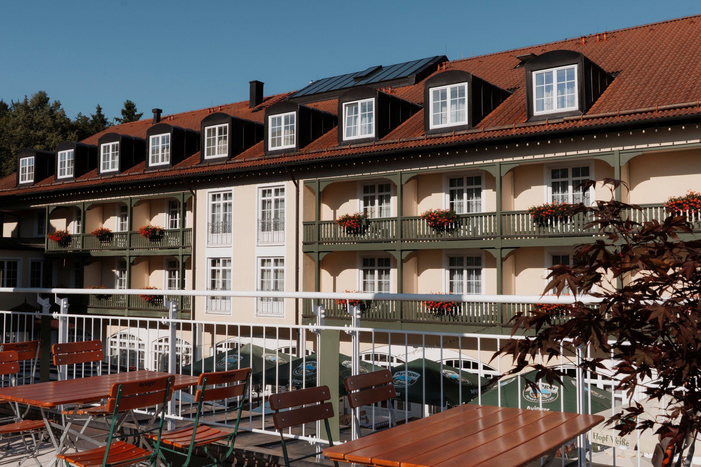 Der Bayerische Hof: Fassade mit Holzbalkonen und Geranien über der Sonnenterrasse