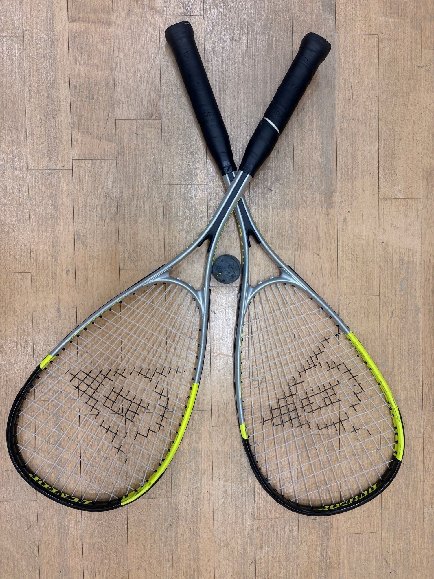 Two squash rackets and a ball on the light wooden floor