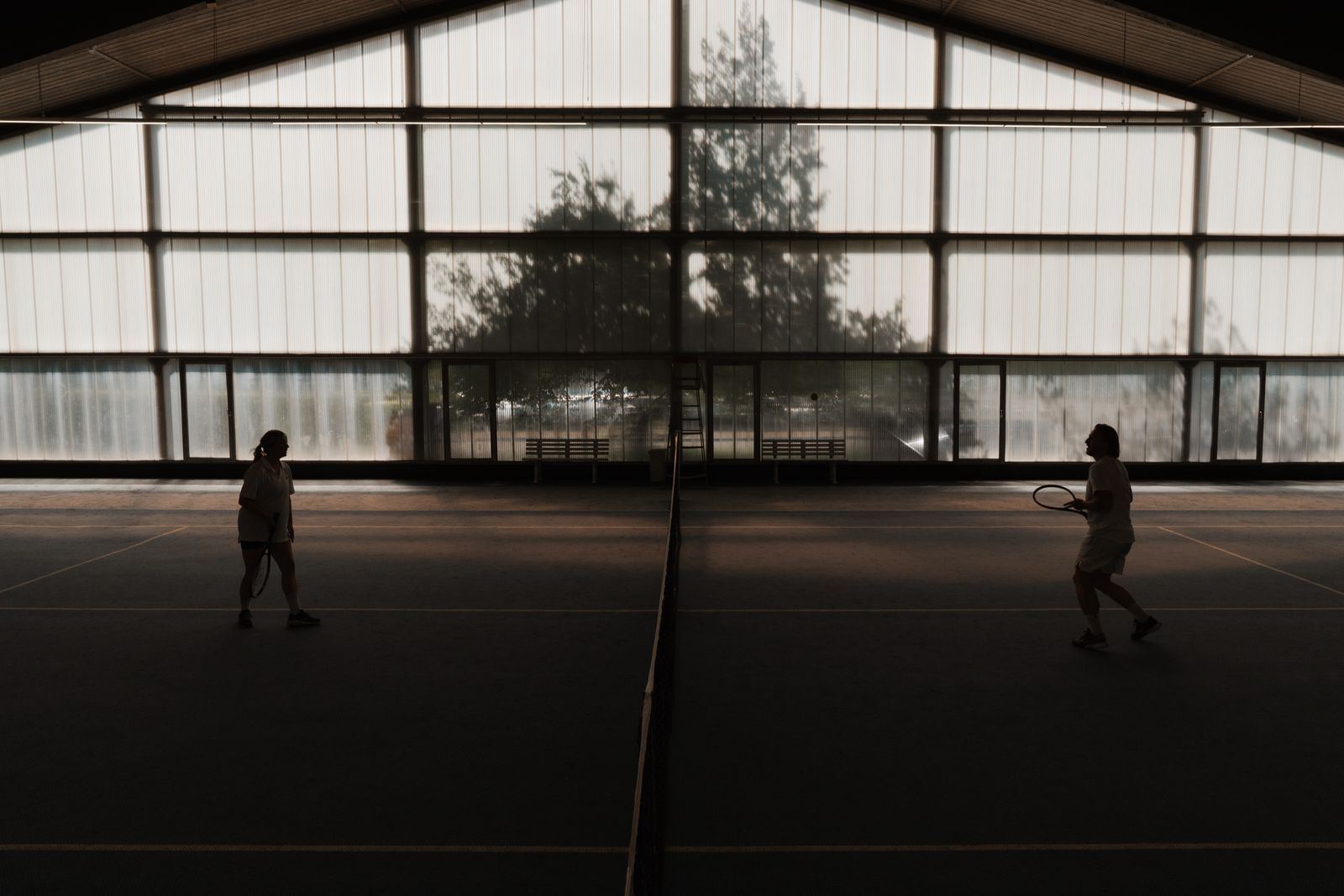 Tennis player in the sports park hall, backlit by the large windows